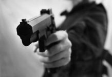 Close-up of a person holding a handgun in a threatening manner