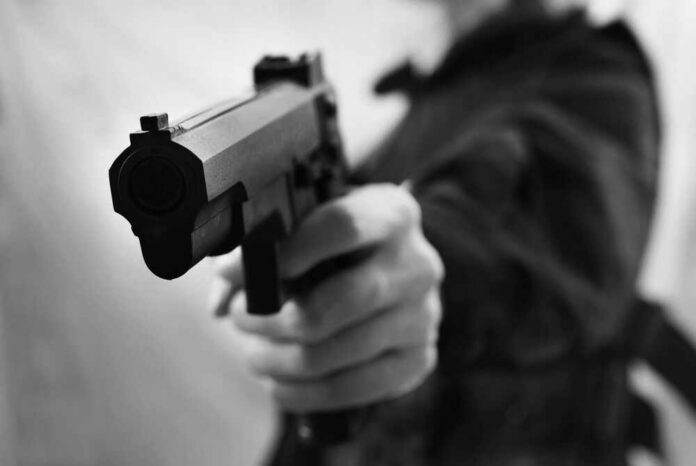 Close-up of a person holding a handgun in a threatening manner