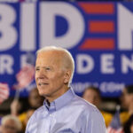 Man in blue shirt at Biden rally with flags