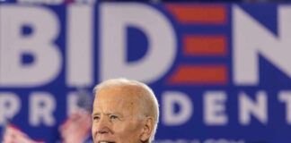 Man in blue shirt at Biden rally with flags