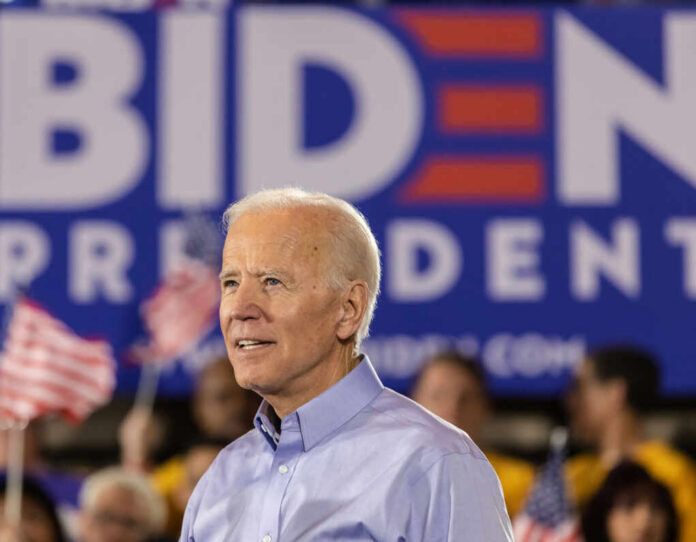 Man in blue shirt at Biden rally with flags