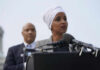 Two people speaking at a podium with microphones