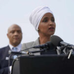 Two people speaking at a podium with microphones