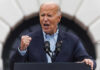 older man speaking passionately at a podium with two microphones