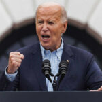 older man speaking passionately at a podium with two microphones