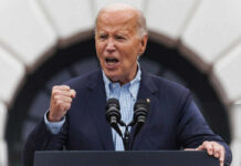 older man speaking passionately at a podium with two microphones