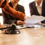 Judge's gavel on desk with legal team reviewing documents