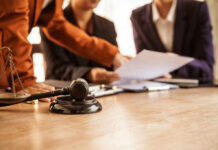 Judge's gavel on desk with legal team reviewing documents
