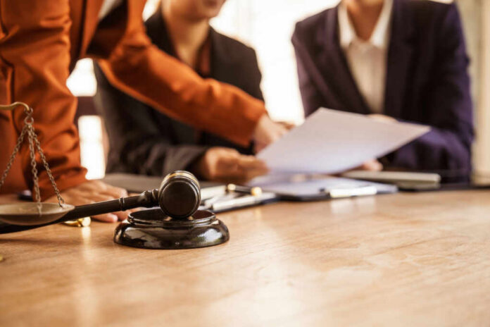 Judge's gavel on desk with legal team reviewing documents