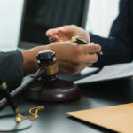 Hands of professionals discussing documents beside a judge's gavel