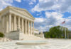 The U.S. Supreme Court building with a fountain in the foreground under a blue sky