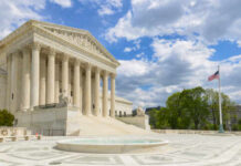 The U.S. Supreme Court building with a fountain in the foreground under a blue sky