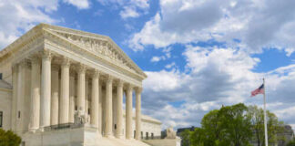 The U.S. Supreme Court building with a fountain in the foreground under a blue sky