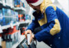 A young man in a colorful jacket crouching in a retail store aisle