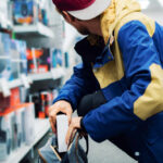 OUTRAGE: Loyal Manager Loses Job Over Shoplifter Incident A young man in a colorful jacket crouching in a retail store aisle