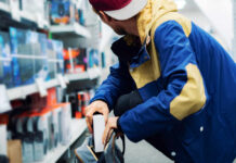A young man in a colorful jacket crouching in a retail store aisle