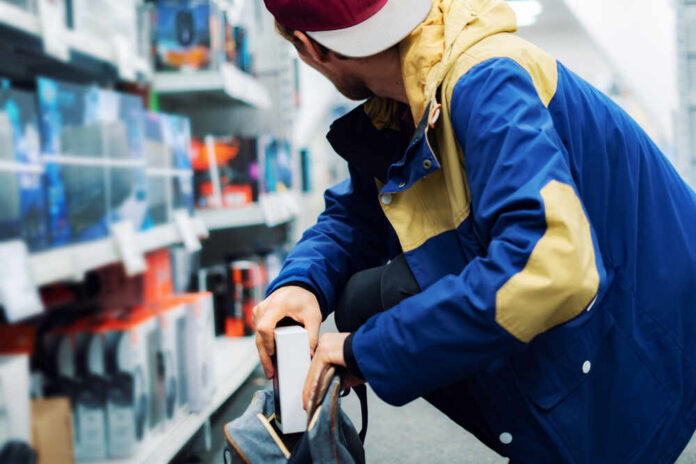 A young man in a colorful jacket crouching in a retail store aisle