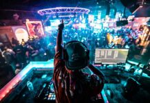 A DJ performing in a vibrant nightclub filled with dancing people