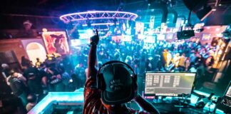 A DJ performing in a vibrant nightclub filled with dancing people