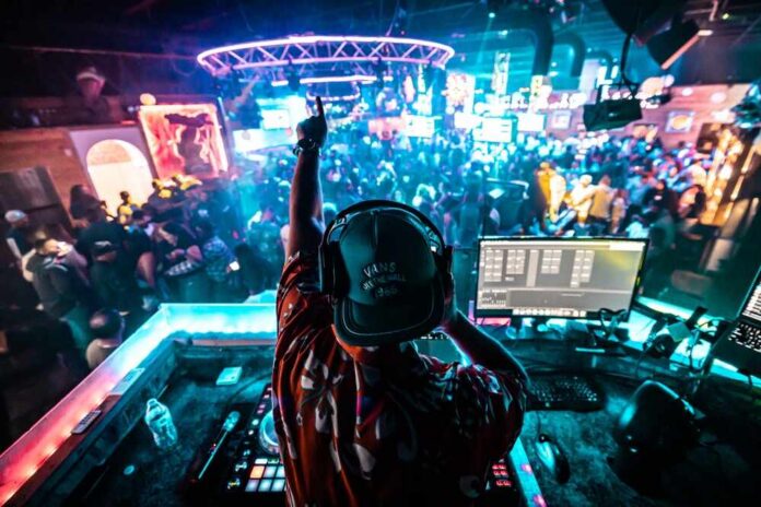 A DJ performing in a vibrant nightclub filled with dancing people