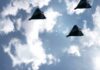 Three drones flying in a cloudy sky