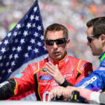 Race car drivers discussing with an American flag in the background