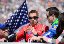 Race car drivers discussing with an American flag in the background