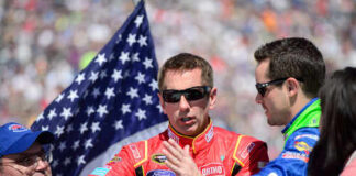 Race car drivers discussing with an American flag in the background