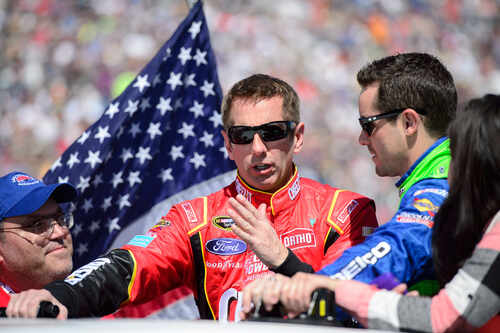 Race car drivers discussing with an American flag in the background
