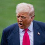 Trump’s Surprising Pause—What’s Behind It? A political figure speaking outdoors with an expressive gesture