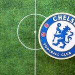 Chelsea Football Club logo on a soccer field background