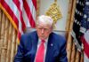 Donald Trump seated in the Oval Office with a serious expression