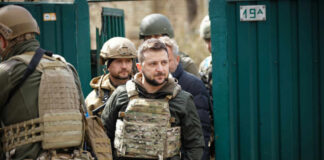 Man wearing tactical gear with military personnel around