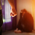 Person with clenched fist confronting a curled-up figure.