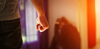 Person with clenched fist confronting a curled-up figure.