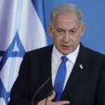 Fury On The Line: Trump Hammers Netanyahu Man speaking in front of Israeli flag backdrop