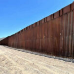 Commissioner Reveals Border Wall Endgame Tall border fence beside a dirt road desert