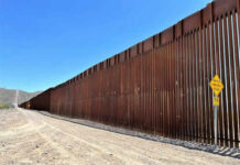 Commissioner Reveals Border Wall Endgame Tall border fence beside a dirt road desert