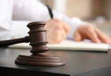 Battery Charge Sparks Judicial Meltdown Wooden judge's gavel on a desk with a person writing in the background