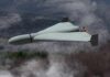 Flying wing drone with pusher propeller over foggy forest