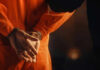 Person in orange jumpsuit with hands cuffed behind back