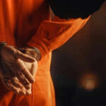 Chinese Spycraft Infiltrates California Person in orange jumpsuit with hands cuffed behind back