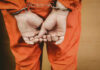 Fort Eisenhower Killing Ends in Admission Person in orange jumpsuit with handcuffs behind back