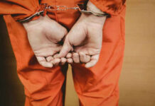 Fort Eisenhower Killing Ends in Admission Person in orange jumpsuit with handcuffs behind back