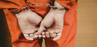 Person in orange jumpsuit with handcuffs behind back