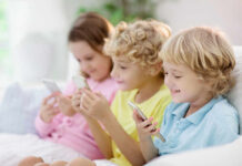 UK Child Ban, Adult Tracking? Three children sitting together, each using a smartphone