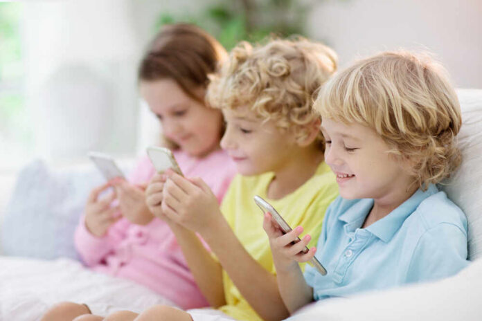 Kids,With,Mobile,Phone.,Child,With,Tablet,Computer,Watching,Movie Three children sitting together, each using a smartphone