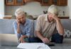 Senior couple looking stressed while reviewing financial documents at home