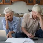 Senior couple looking stressed while reviewing financial documents at home