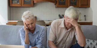Senior couple looking stressed while reviewing financial documents at home